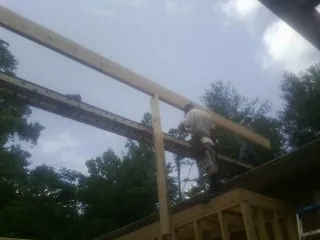 Carpenter setting a ridge beam over a new addition frame — Ice Dam Removal by Roofing Brothers in Poca