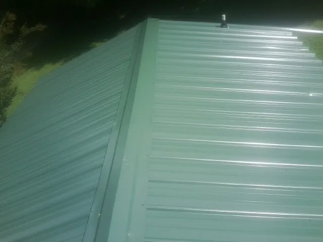 New green metal panels meeting at the ridge of a roof — Flat Roof Repair work by our crew in Poca