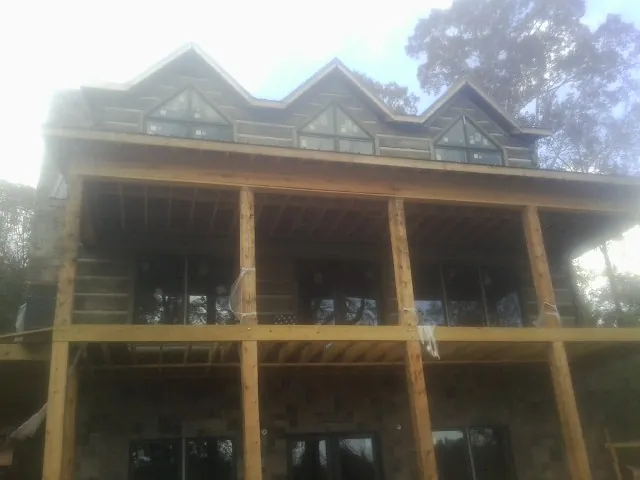 Dormers and porch framing on a large log home under construction — Roof Coating work by our crew in Poca