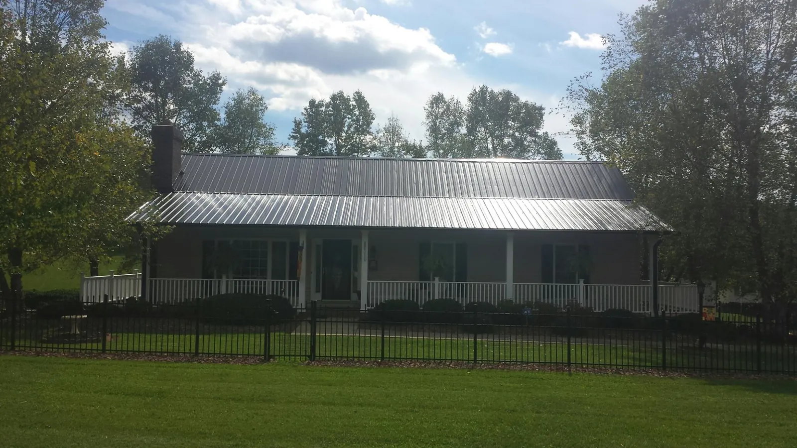 Gray metal roof on a brick ranch with a full width front porch — Gutter Guard Installation work by our crew in Poca
