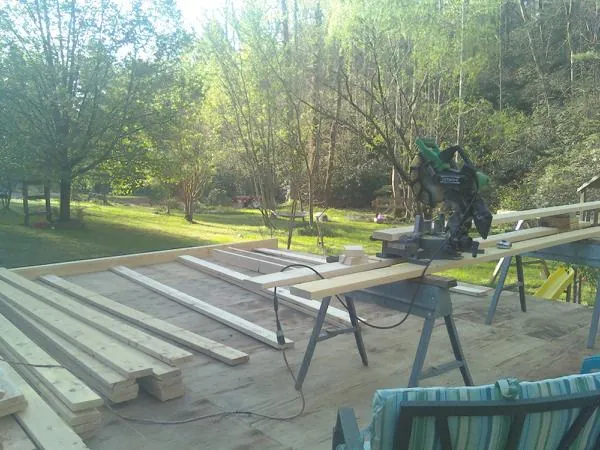 Miter saw and framing lumber on a deck under construction in Poca