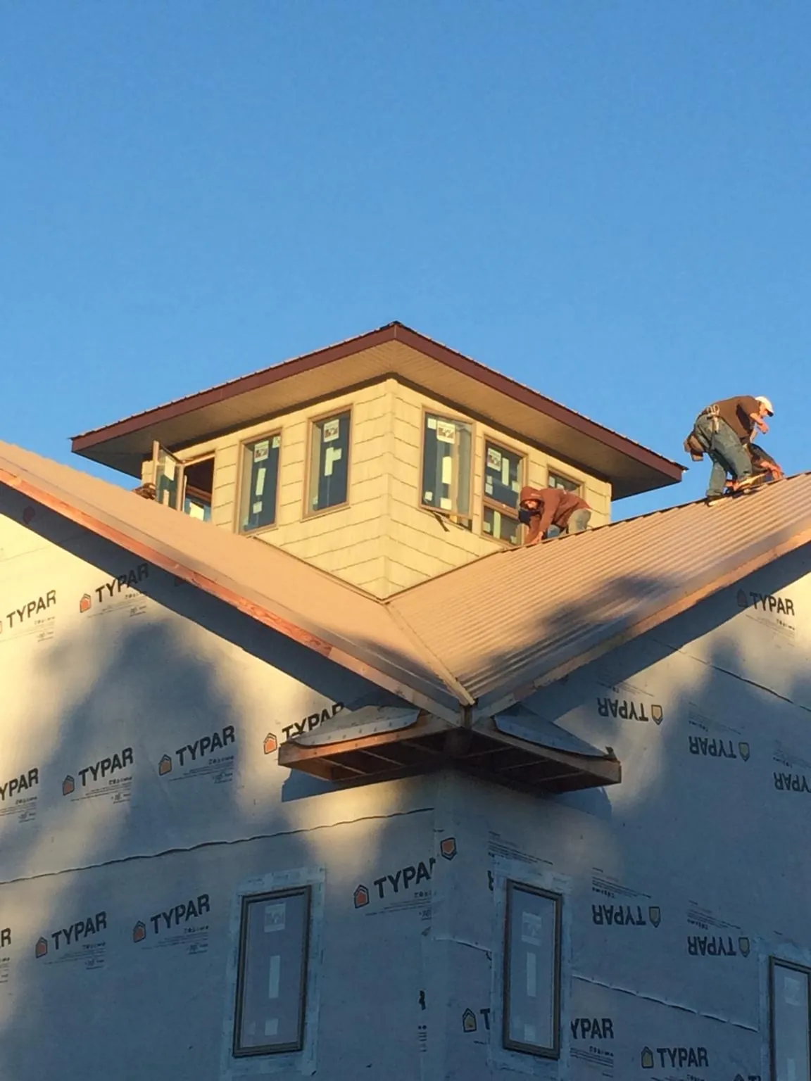 Roofers working around a rooftop cupola on a new metal roof at sunset — Roof Waterproofing in Poca by Roofing Brothers